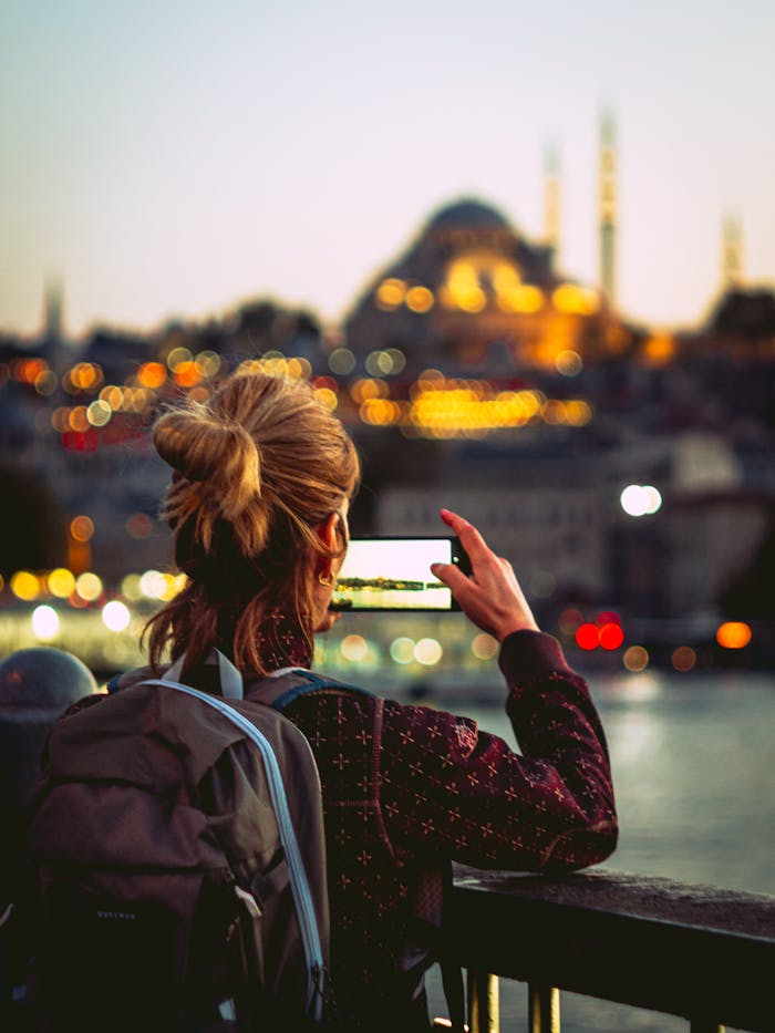 A woman takes a photo of a mosque in Istanbul with a smartphone.