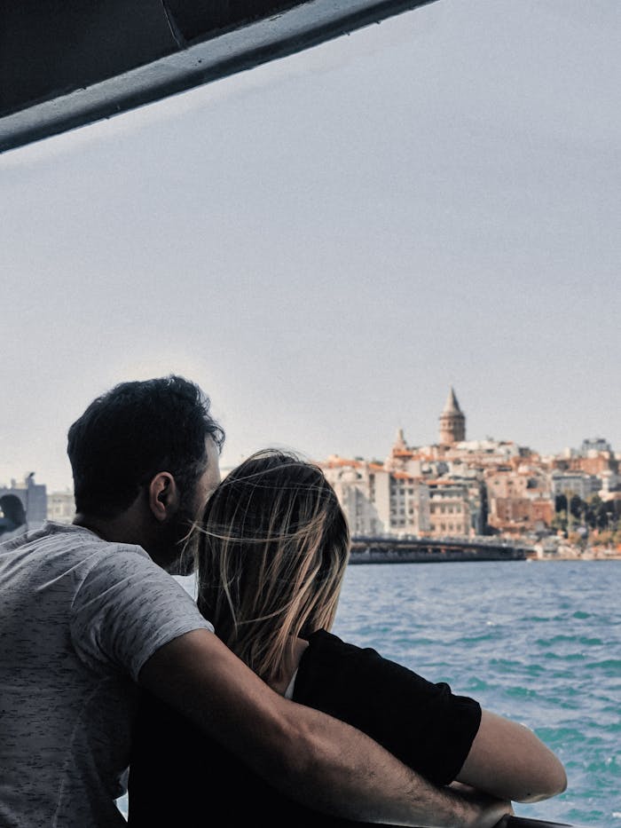 Couple enjoying a scenic view of Istanbul's skyline and Galata Tower from the sea.